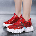 Red glittery sneakers with white soles worn by a person on a gray floor.