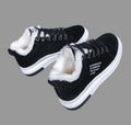 Side view of a pair of Sienna Cozy Plush-Lined Platform Sneakers in Black, showcasing the smooth black uppers, black lace-up closures, warm contrasting white faux-fur style lining, rounded toe shape, and elevated white platform soles for casual cold-weather styling.