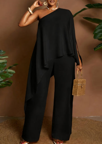 Amara women's elegant black two-piece pants set shown from the front, featuring an asymmetrical one-shoulder top with a flowing cape-style overlay, draped fabric across the torso, and coordinating solid black wide-leg trousers.