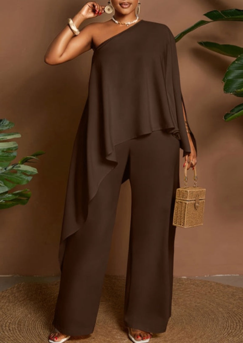 Amara women's brown one-shoulder pants suit featuring a dramatic asymmetrical draped cape top, one exposed shoulder, flowing layered fabric, and matching relaxed wide-leg trousers styled as an elegant evening outfit.