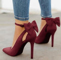 Dark Red Arielle Bow Ankle-Strap Stiletto Pumps worn with cropped denim, featuring oversized deep red ankle bows, pointed toes, and slim stiletto heels for a rich Fall and Winter statement look.