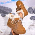 Women’s camel Aspen Luxe fleece-lined snow boots featuring warm plush lining, decorative bow and buckle accents, rounded toes, and thick platform soles shown against a snowy winter background.