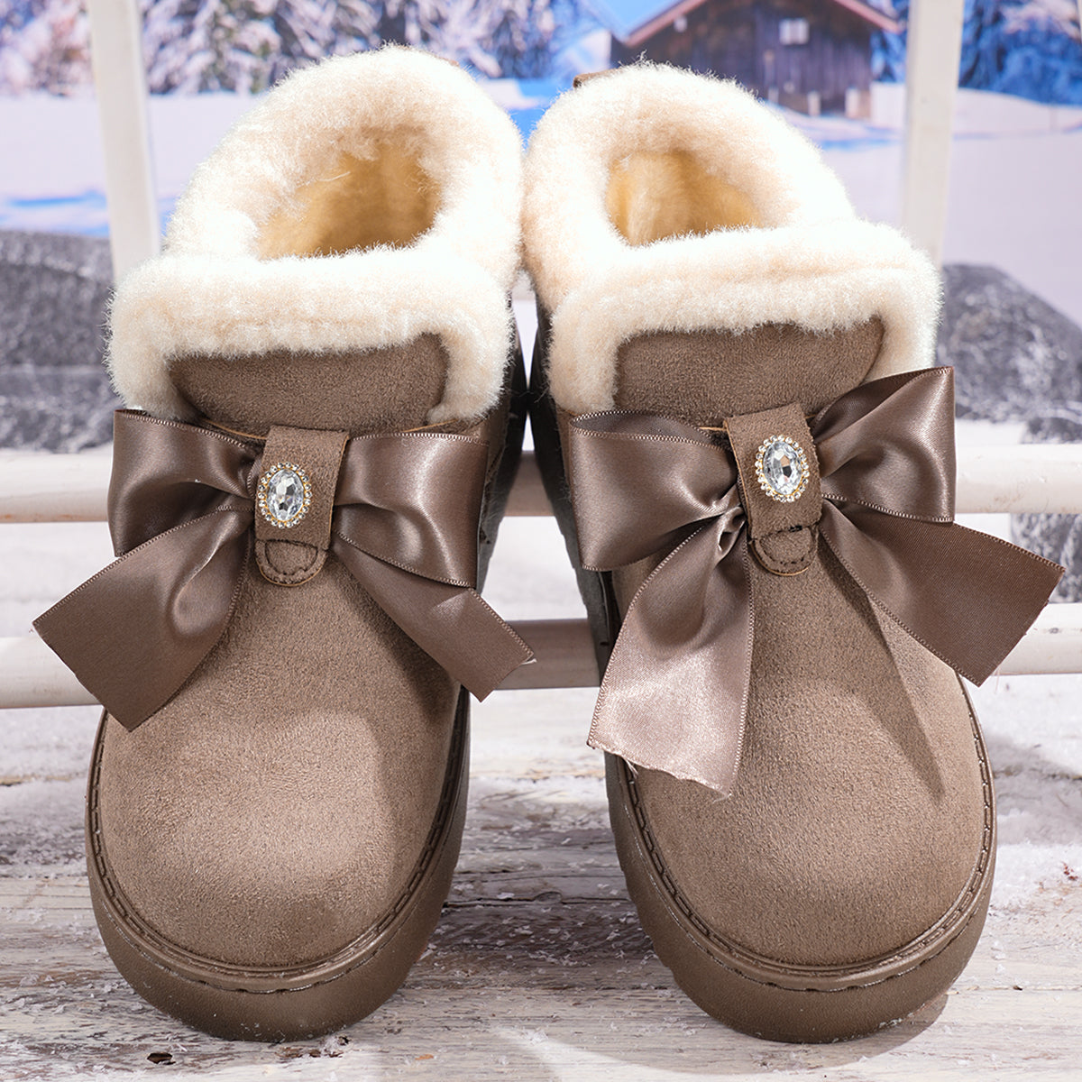 Women’s gray Aspen Luxe platform snow boots featuring plush white fleece lining, an oversized bow accent, buckle hardware, rounded toes, and thick textured platform soles.