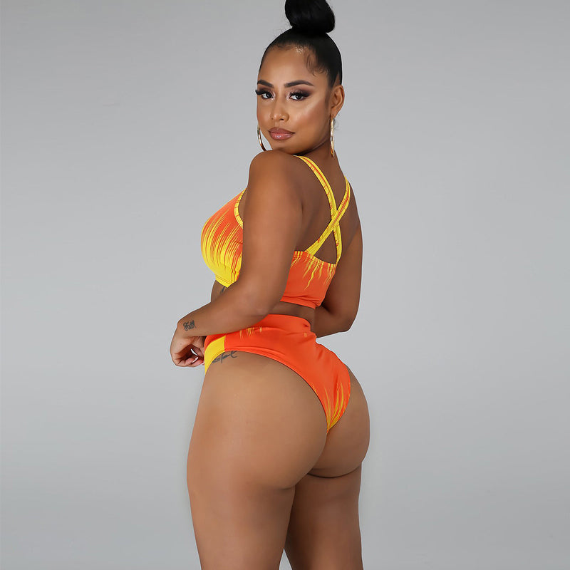 Azaria blue-and-yellow bikini shown from a rear side view, featuring a vibrant gradient-print cropped top with crisscross back straps and matching high-waisted bottoms with high-cut legs.