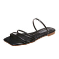 Black women’s minimalist flat sandals featuring multiple slim black straps across the toes and forefoot, an open square-toe design, coordinating black footbed, and low flat sole, shown from an angled side view against a clean white background.