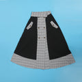 Detail view of plaid panels and button accents on asymmetrical midi skirt.
