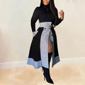 Woman wearing black turtleneck with plaid asymmetrical midi skirt and tall black boots.