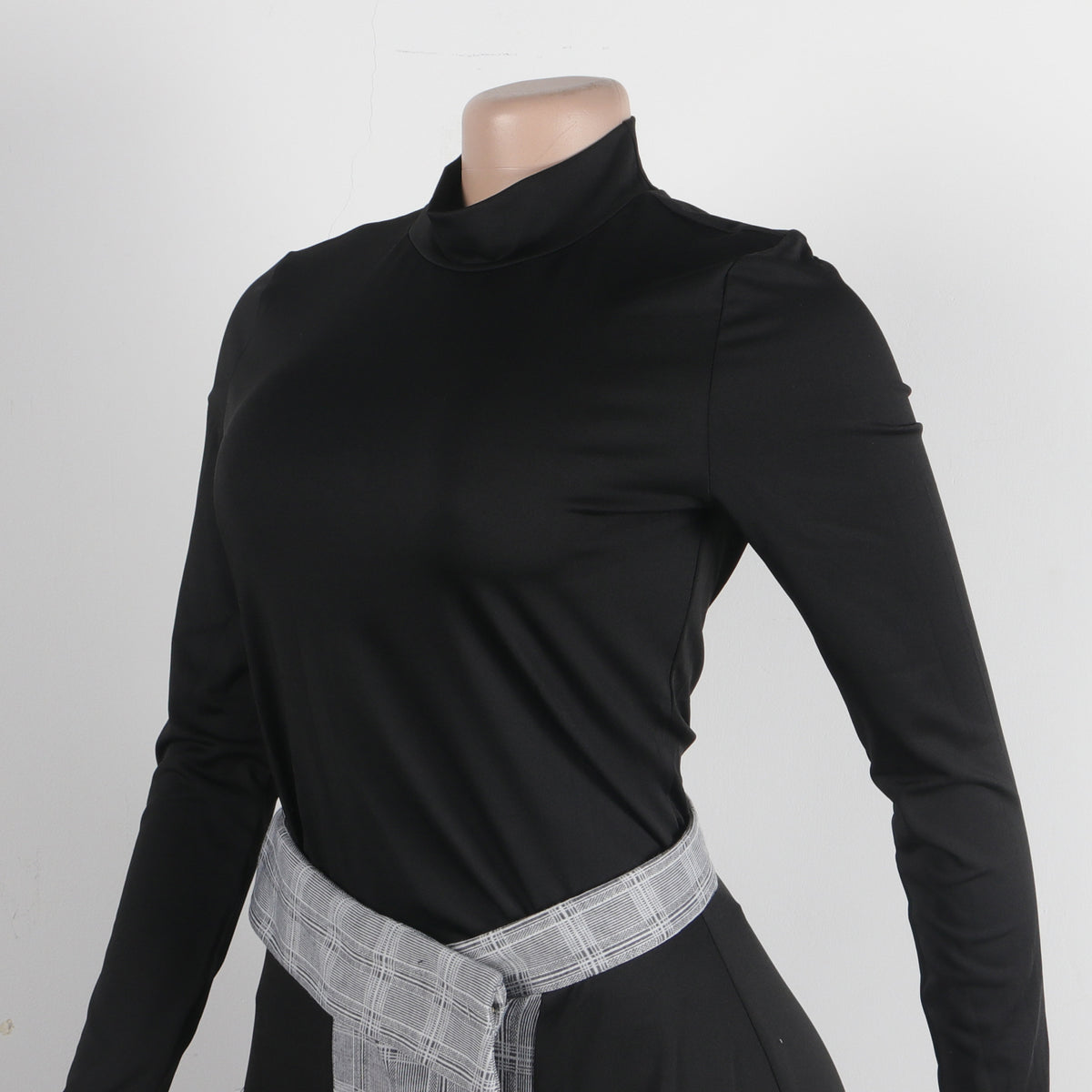 Side view of women's black and plaid asymmetrical two-piece skirt set.