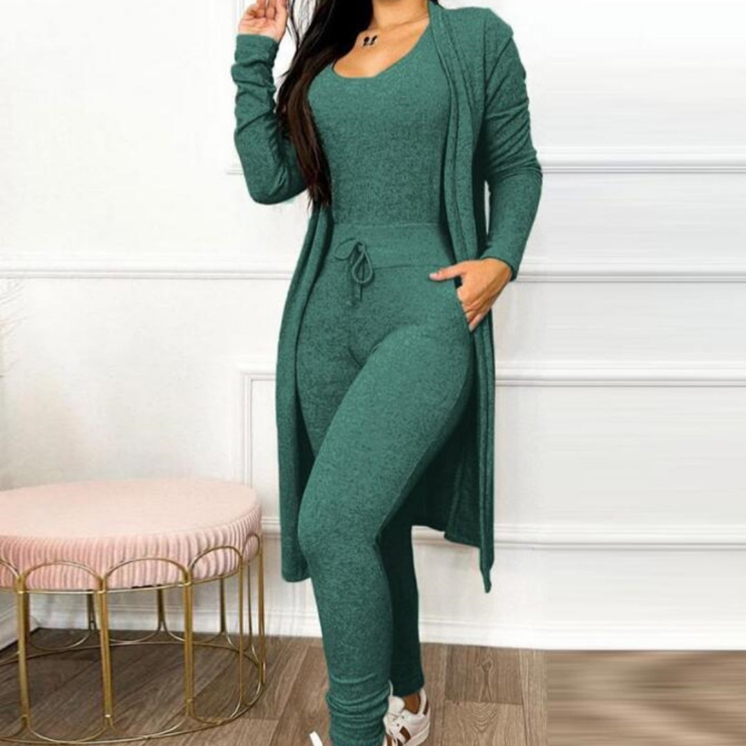 Brielle women's cozy knit-look jumpsuit and long cardigan sets displayed side by side in green, navy blue, and charcoal black, featuring fitted sleeveless scoop-neck jumpsuits with adjustable drawstring waists, tapered pant legs, and matching long-sleeve open-front cardigans extending below the hips, styled with white casual sneakers.