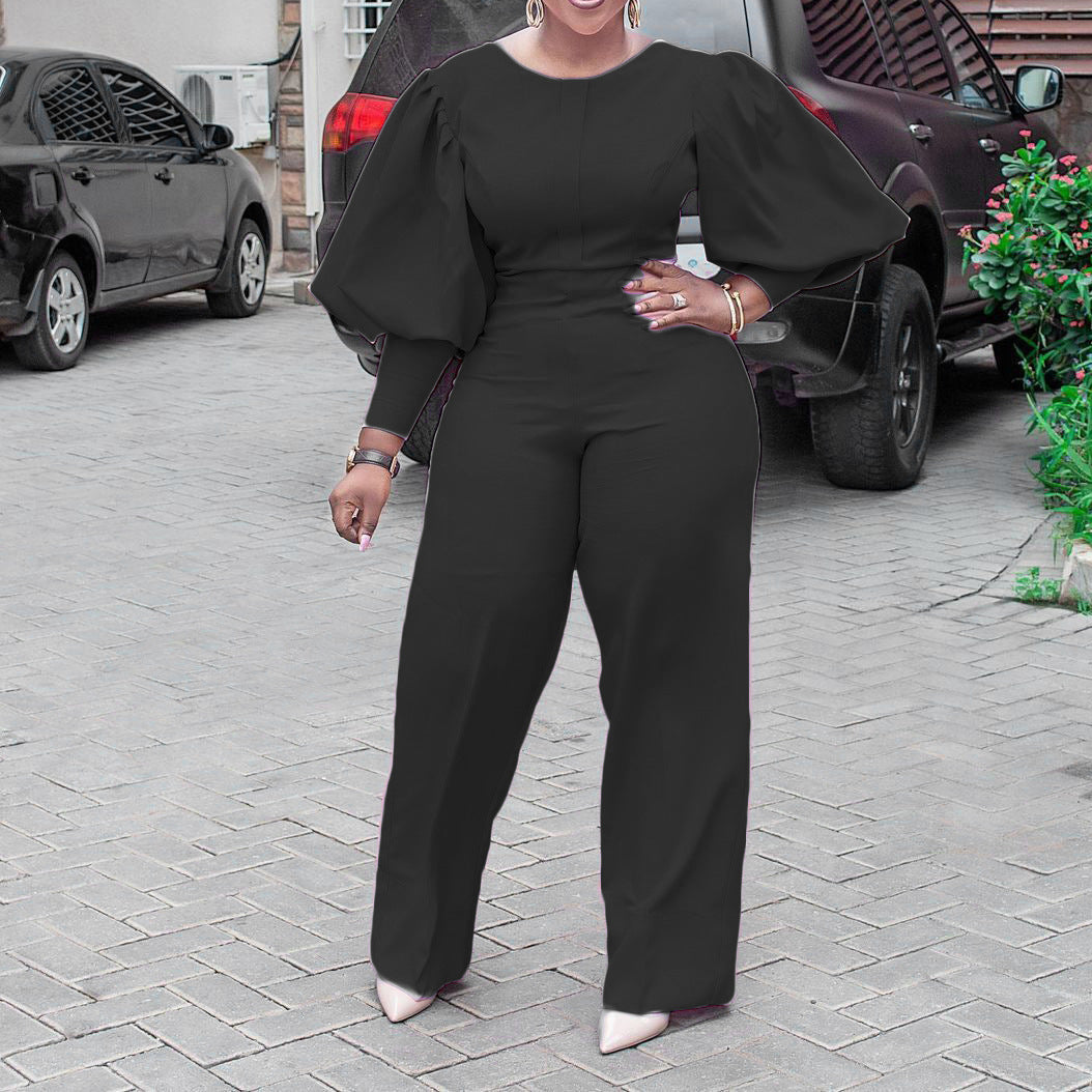 Detail view of the Cambria women's black jumpsuit focusing on the voluminous puff sleeve construction, smooth bodice, fitted waist shaping, and the clean transition into wide-leg trousers.