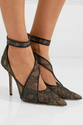 Black Celeste Lace Pointed-Toe Stiletto Pumps worn on a model, showing the semi-sheer lace design across the foot, pointed toes, secure ankle straps, and slender high heels.