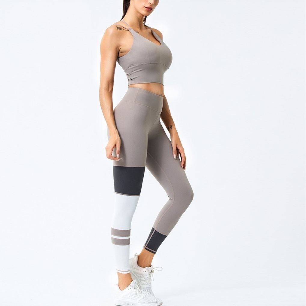 Woman wearing a khaki athletic outfit with leggings and a crop top on a white background