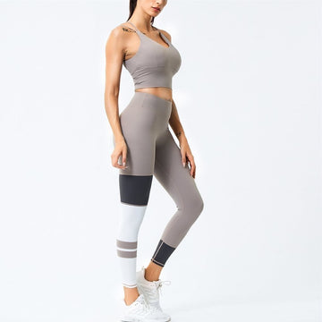Woman wearing a khaki athletic outfit with leggings and a crop top on a white background