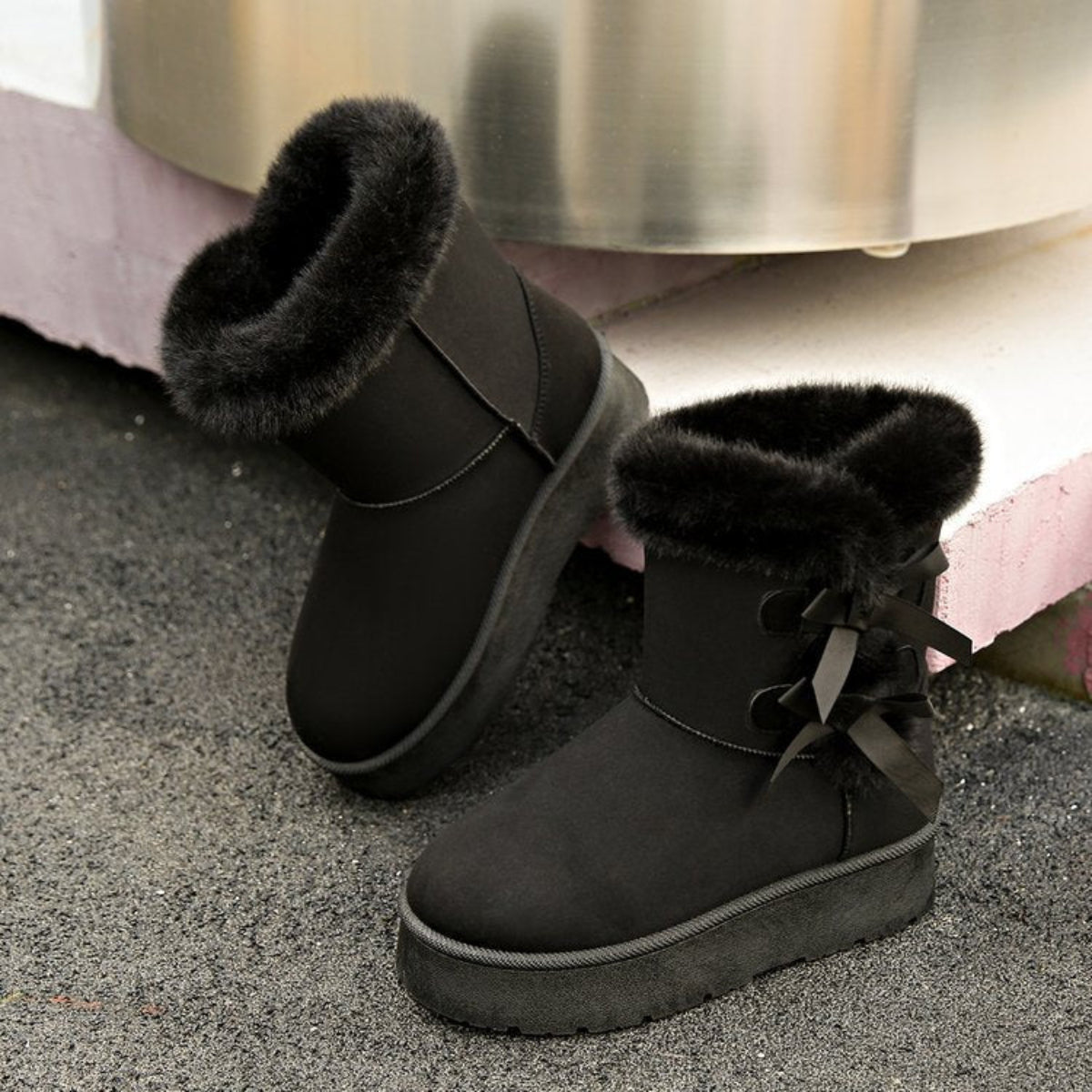 Woman wearing black Cozy Belle fleece-lined ankle boots with dark skinny jeans, showcasing the plush cuff, side bow embellishment, rounded toe, and casual winter silhouette.
