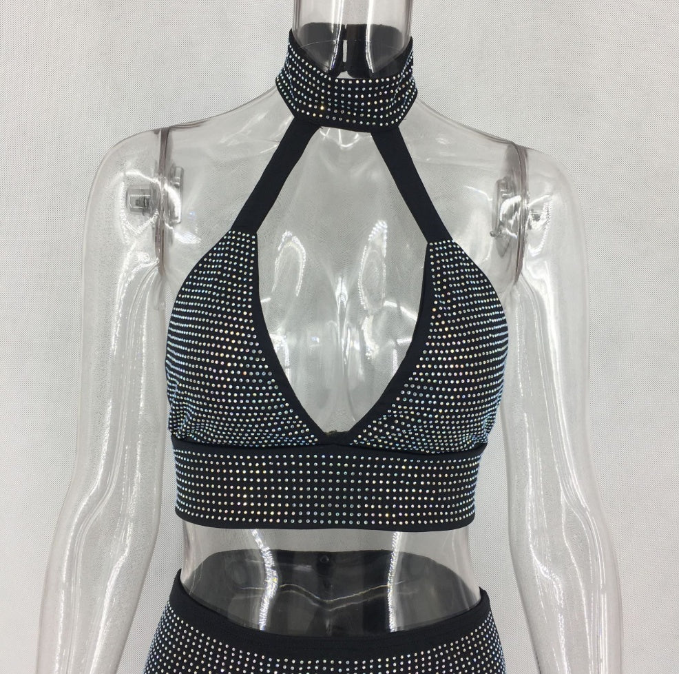Woman wearing crystal rhinestone halter crop top and matching fitted mini skirt.