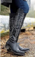 Woman wearing black Dakota embroidered Western knee-high boots outdoors with fitted jeans, showcasing the tall shaft, detailed Western embroidery, pointed-toe silhouette, and wearable low heel.