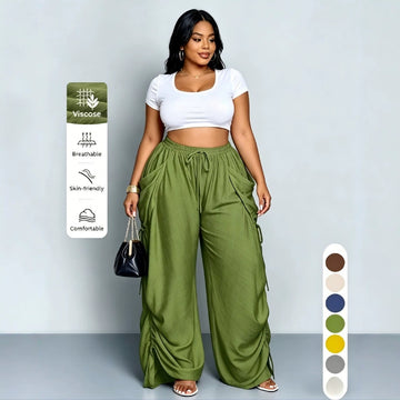 Delilah women's army green high-waisted ruched cargo pants shown on a model, featuring a loose oversized fit, gathered drawstring waistband, large cargo-style side pockets, adjustable fabric ruching along the outer legs, and flowing wide-leg hems that create a relaxed streetwear silhouette.