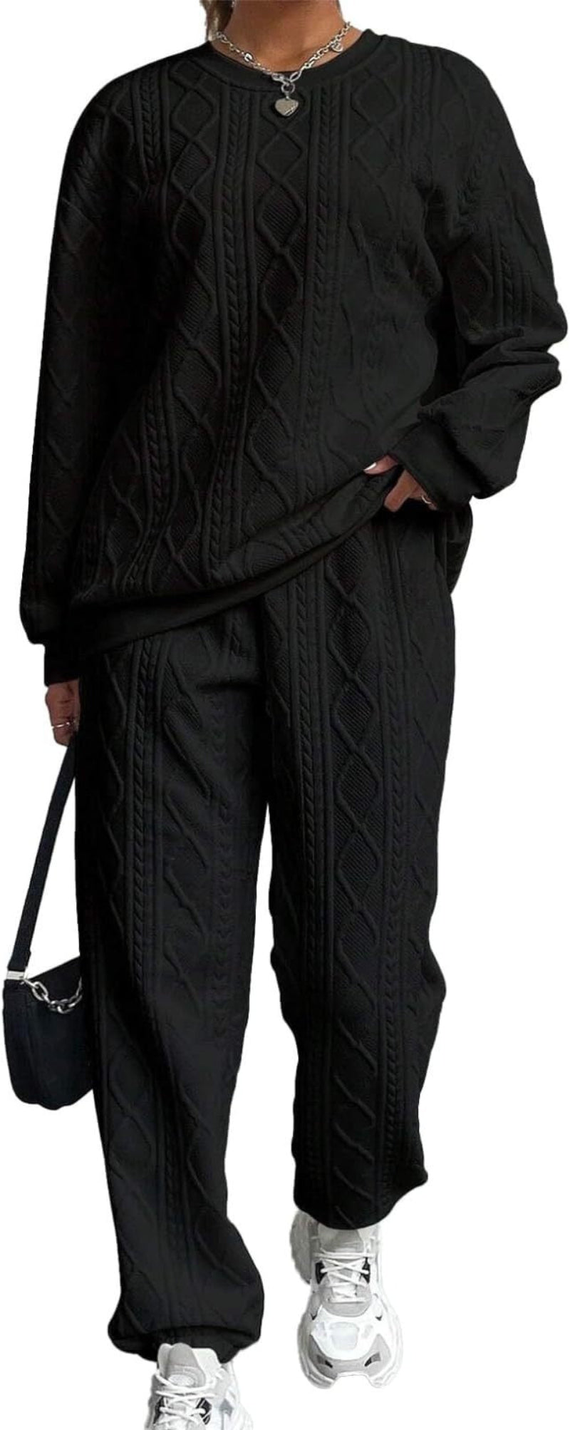 Harper women's black cable-knit two-piece lounge outfit shown in a full-body standing pose, featuring a relaxed long-sleeve crewneck sweater with subtle textured knit detailing, matching black drawstring jogger pants with tapered ankles, and white sneakers, accessorized with a black handbag.