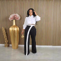 Close-up of Kendra women's high-waisted black-and-white trousers showing the fitted-looking waistband, smooth black fabric through the hips, and distinctive white contrast panel beginning near the waist and extending down the front of the leg for a sleek, fashion-forward appearance.