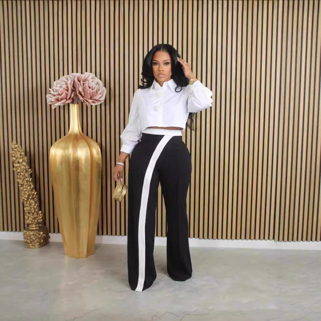 Close-up of Kendra women's high-waisted black-and-white trousers showing the fitted-looking waistband, smooth black fabric through the hips, and distinctive white contrast panel beginning near the waist and extending down the front of the leg for a sleek, fashion-forward appearance.