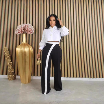 Close-up of Kendra women's high-waisted black-and-white trousers showing the fitted-looking waistband, smooth black fabric through the hips, and distinctive white contrast panel beginning near the waist and extending down the front of the leg for a sleek, fashion-forward appearance.
