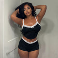 Front view of the Kinsley women's black camisole and matching shorts lounge set, featuring delicate white lace trim along the neckline, slender black shoulder straps, a fitted camisole silhouette, and coordinating black shorts with white lace edging.