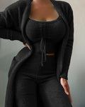 Naomi women's black three-piece pants outfit displayed on a model, featuring a square-neck cropped top with a center drawstring detail, matching long-sleeve cardigan with curved front trim, exposed midriff, and fitted high-waisted black pants with ribbed texture.