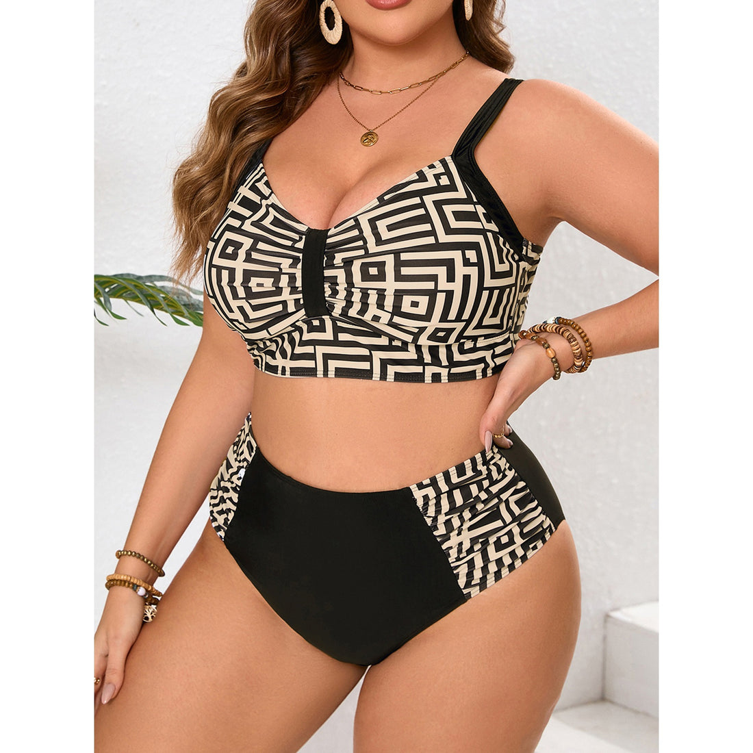 Front view of a curvy model wearing a black-and-cream geometric printed bikini top with wide black straps and matching high-waisted bottoms featuring solid black front and patterned side panels.