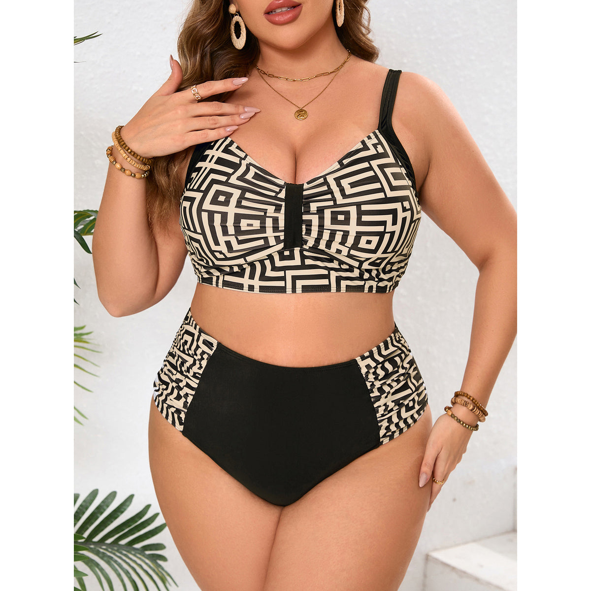 Front view of a curvy model wearing a black-and-cream geometric printed bikini top with wide black straps and matching high-waisted bottoms featuring solid black front and patterned side panels.