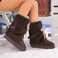 Women’s brown Noelle Bow fleece-lined platform snow boots featuring a soft fuzzy upper, oversized ribbon bow, decorative ankle strap, rounded toes, and thick platform soles.