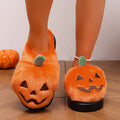 Orange pumpkin Halloween house slippers for women shown from a slightly elevated front view, featuring soft plush pumpkin-shaped uppers, black embroidered jack-o’-lantern faces, small green stems, open-back design, and chunky black soles clearly visible beneath both slippers.