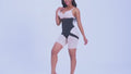 Model wearing a black waist trainer over nude shapewear shorts