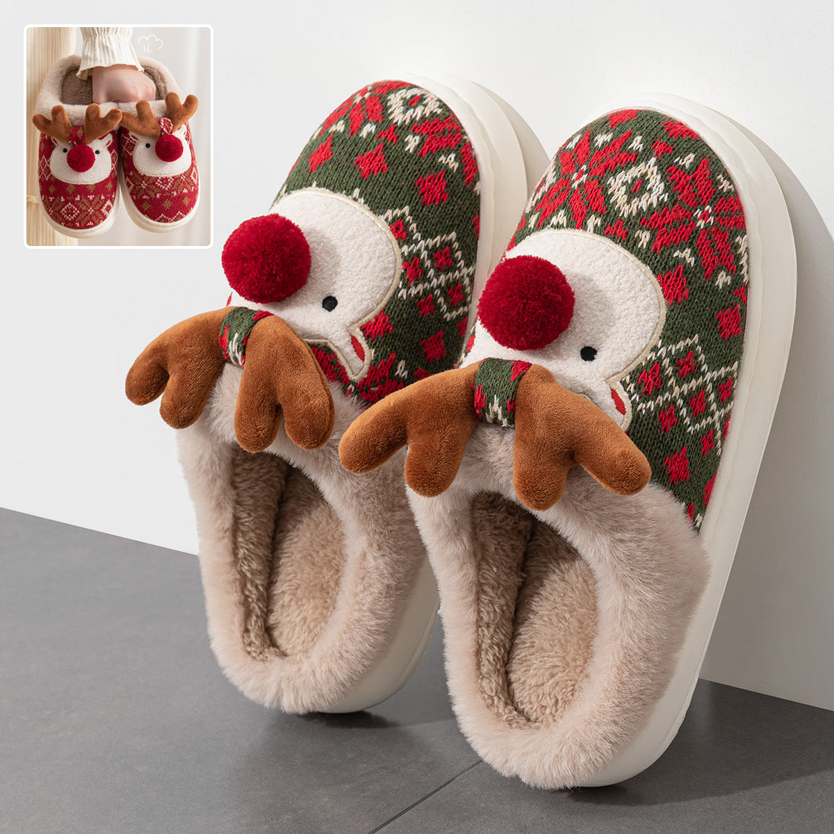 Women’s red and green Christmas plush slippers featuring a festive holiday print, raised 3D reindeer faces with brown antlers, soft red pom-pom noses, beige fuzzy trim, and cozy open-back construction, displayed together from the front for a clear view of the decorative reindeer details and seasonal pattern.