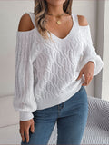 Woman wearing a white cold-shoulder V-neck textured knit sweater with blue jeans in a front view indoors.