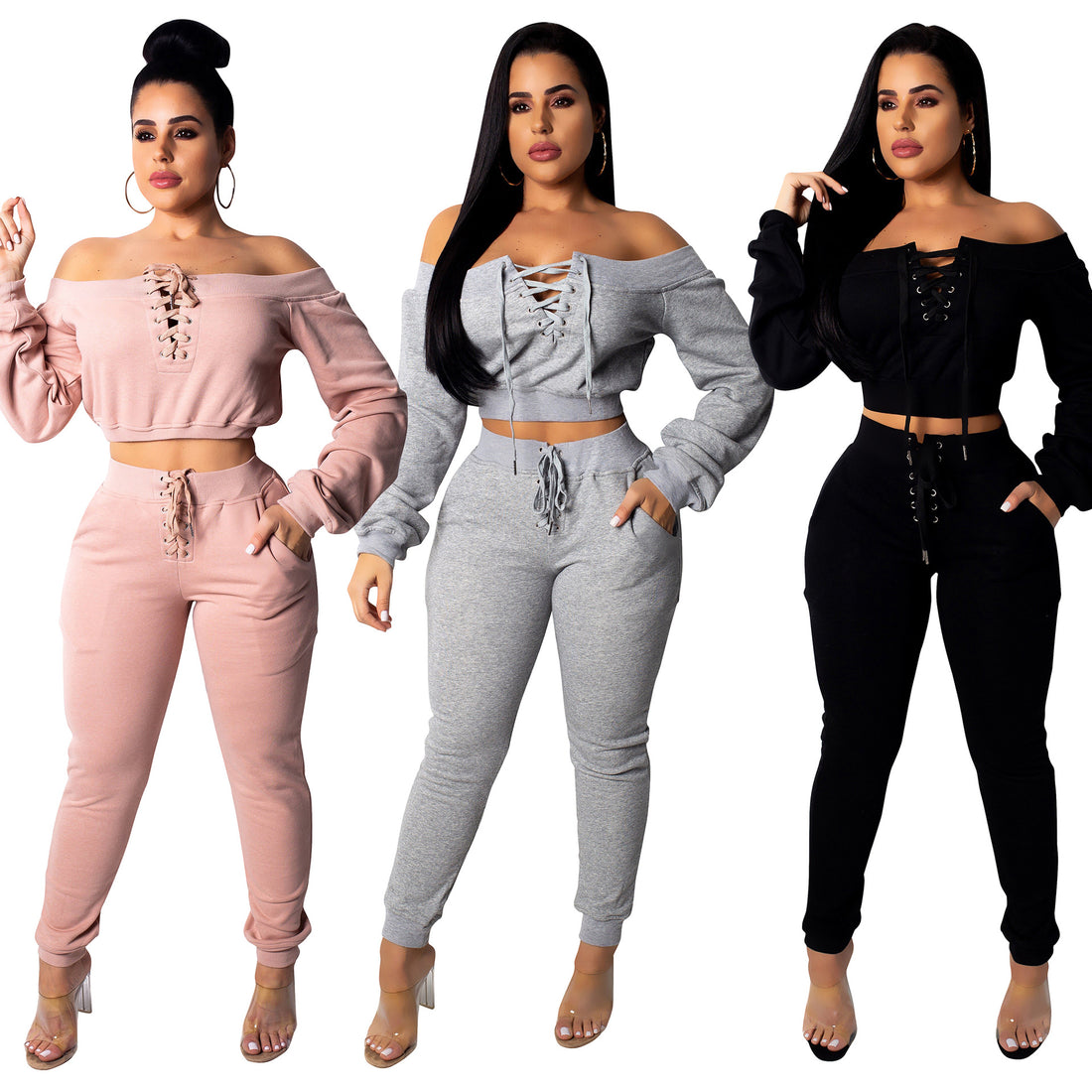 Three women wearing matching Pink, Grey, and Black off-shoulder lace-up cropped tops with coordinating jogger pants against a white background.