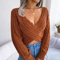 Front view of woman wearing a cinnamon brown twist-front V-neck cropped knit sweater with blue jeans.