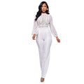 Seraphina women's elegant white evening jumpsuit shown from the front, featuring a high lace-trimmed neckline, intricate floral and geometric lace detailing across the bodice, long sheer white sleeves with gathered cuffs, a defined waist, and matching white straight-leg trousers.