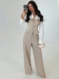 Sloane women's beige tailored vest and wide-leg pants set shown on a model in a standing pose, featuring a fitted button-front beige vest over a white collared blouse, long flared cuffs, and matching floor-length wide-leg trousers.
