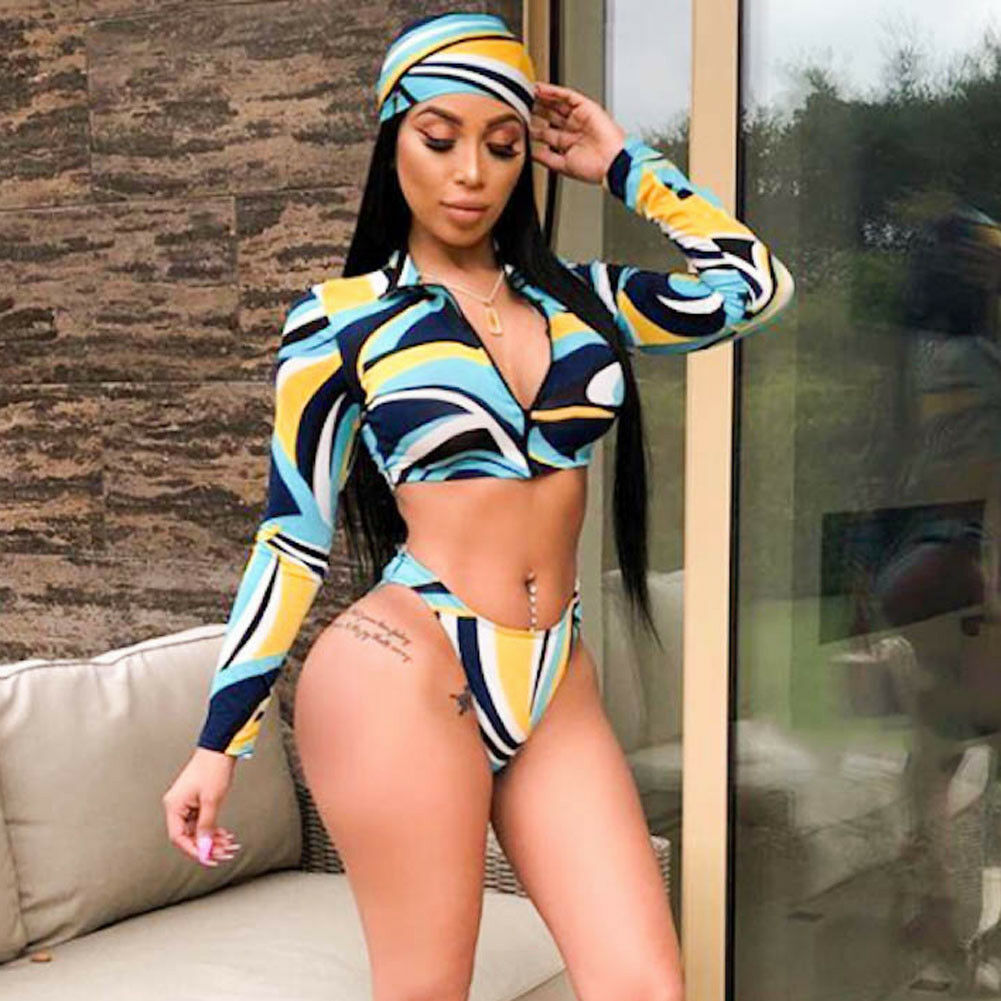 Full front view of a model wearing a cropped long-sleeve bikini top with swirling blue, yellow, black, and white abstract patterns and matching high-cut bikini bottoms.