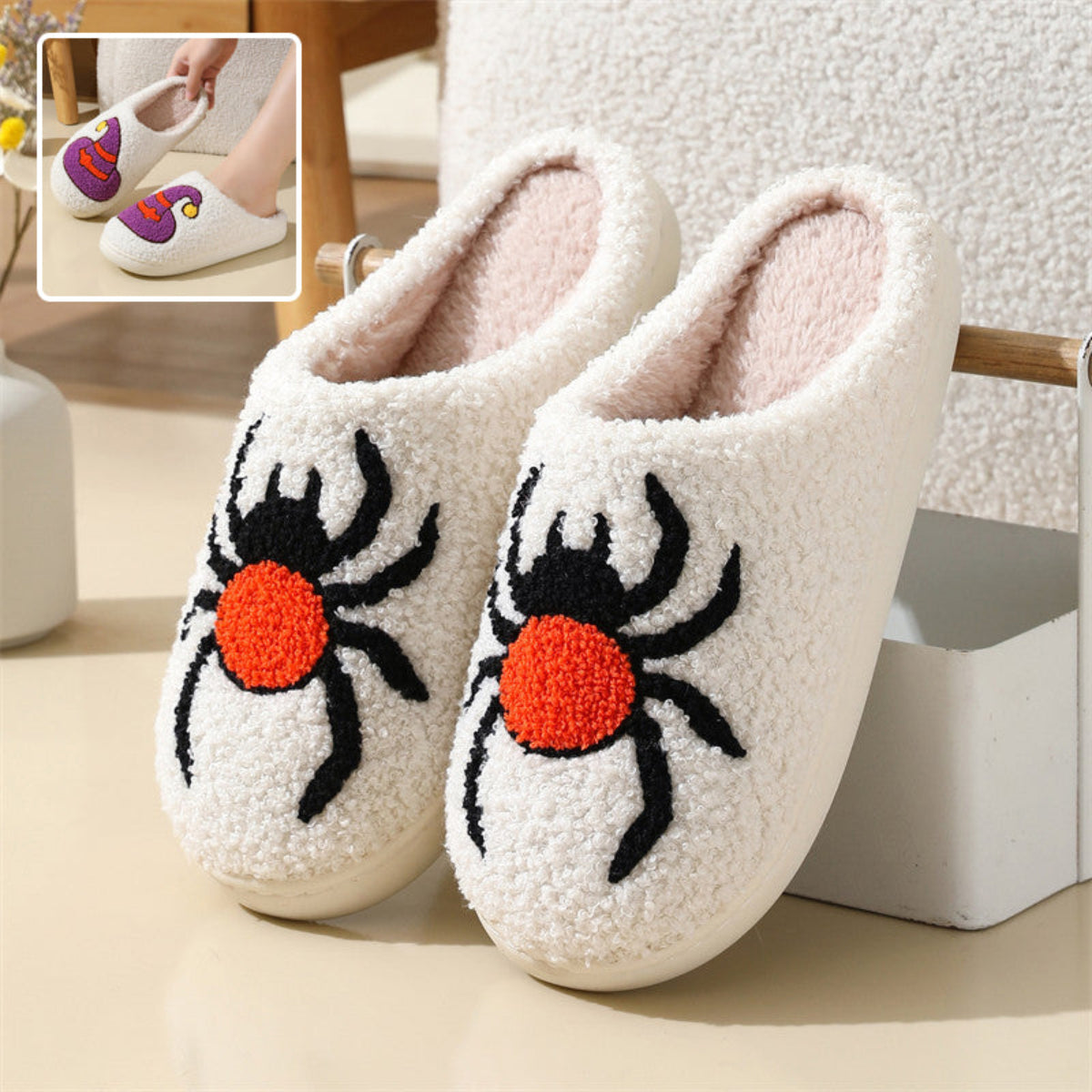 Cream women’s plush Halloween slippers featuring large embroidered black spiders with bright orange-red bodies across the front, a soft fuzzy closed-toe construction, cozy cream lining, and rounded slip-on silhouette, displayed together from the front for a clear view of the bold spider artwork and plush texture.