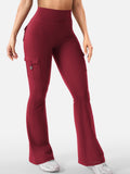 Talia women's wine red high-waisted flare active pants displayed on a model, featuring a smooth fitted waist, close-fitting silhouette, visible back pocket flap details, long flared pant legs, and a rich burgundy-red color that creates a bold athleisure look.