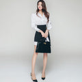 Full-length view of women's white shirt and black asymmetrical skirt outfit.