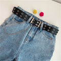 Women’s black double-row grommet chain belt styled with blue denim jeans