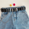 Women’s black double-row grommet chain belt worn around the waist with blue denim jeans