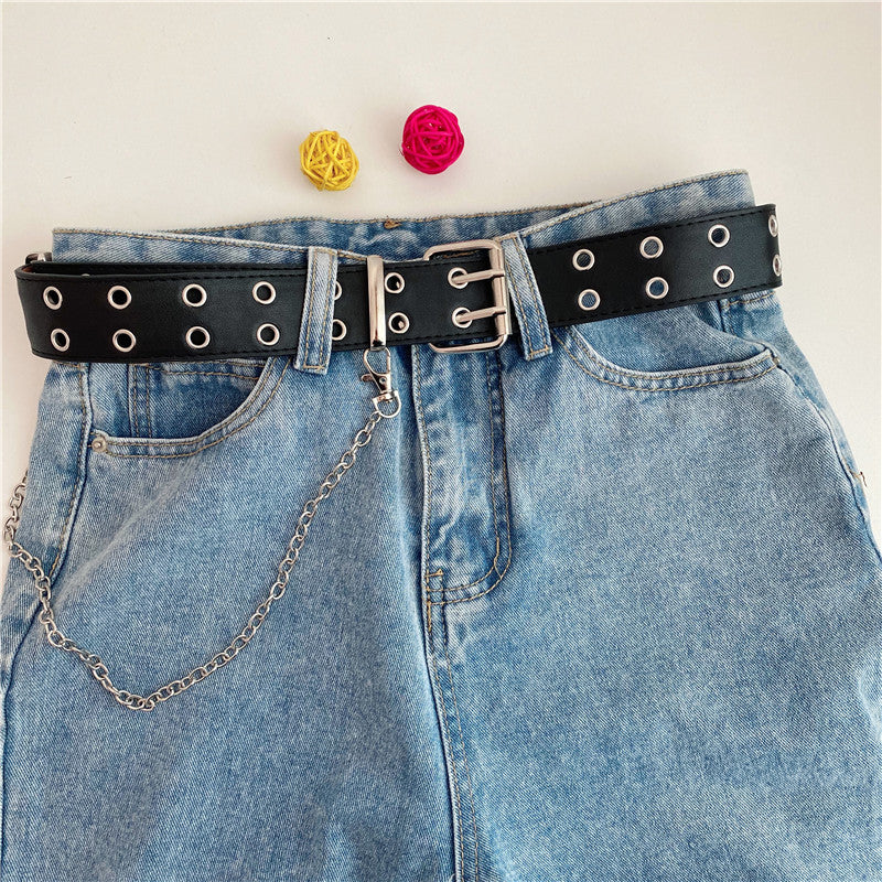 Women’s black double-row grommet chain belt worn around the waist with blue denim jeans