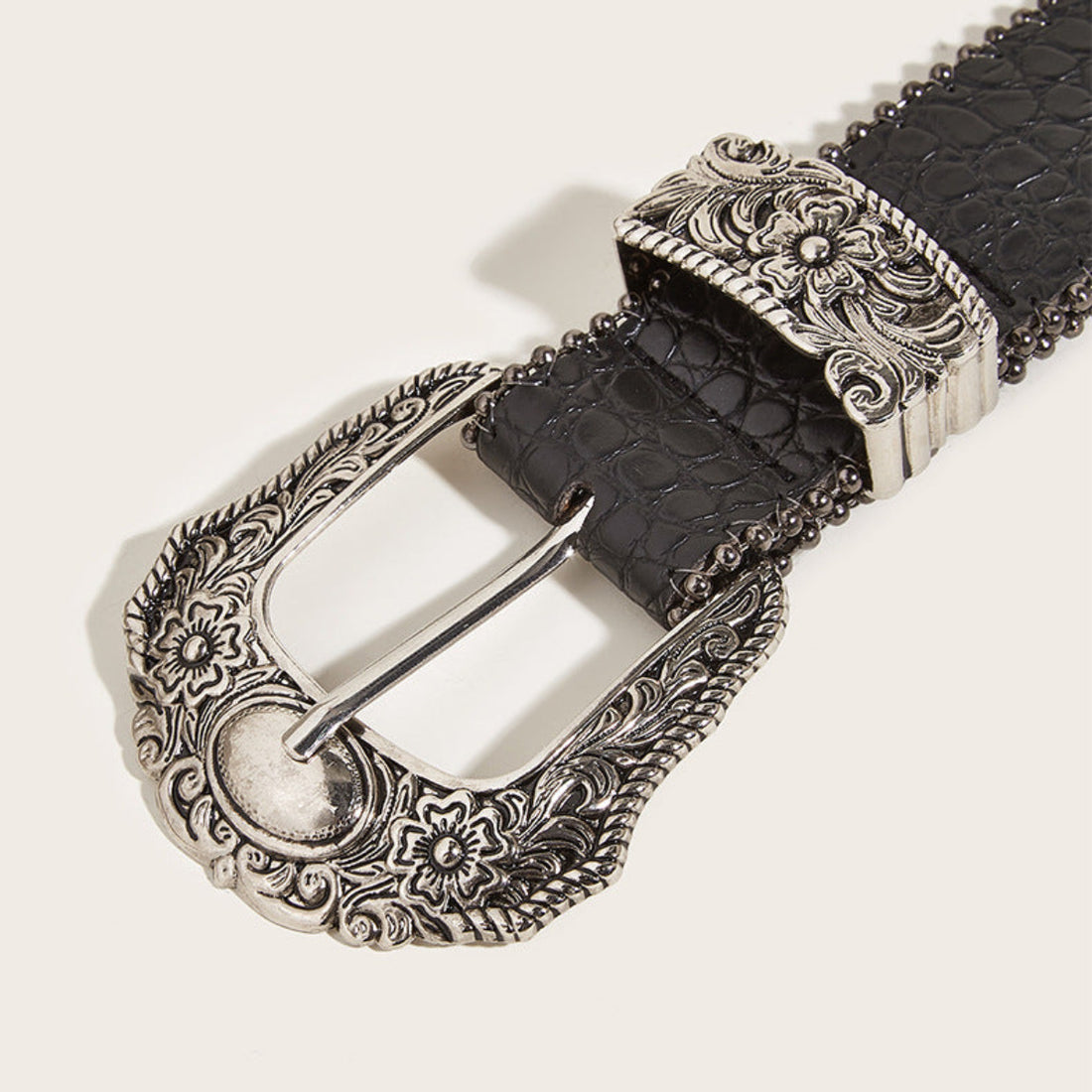 Women’s black Western belt with ornate silver-tone floral buckle and textured finish shown rolled