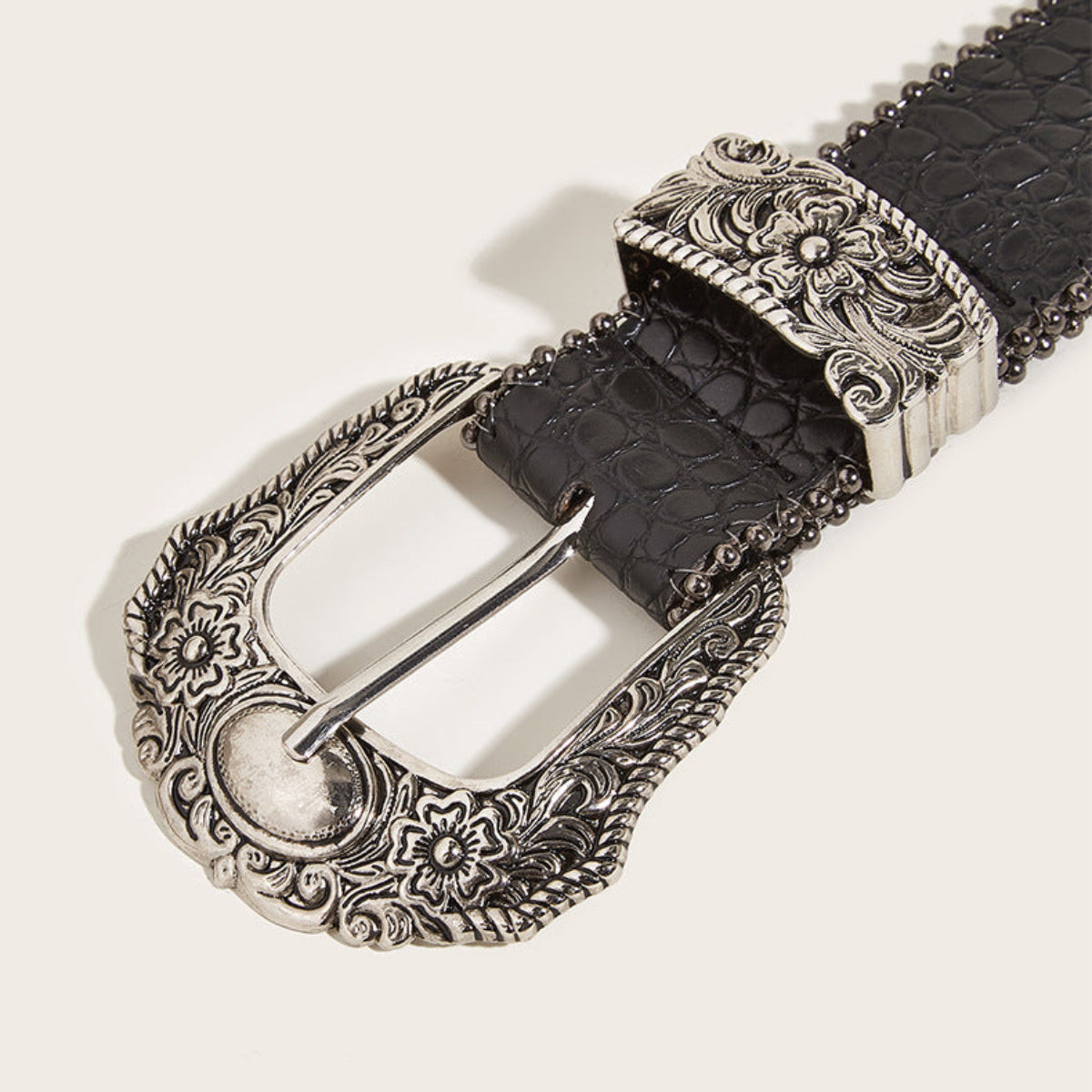 Close-up of women’s black Western belt featuring an ornate silver-tone floral buckle and matching keeper