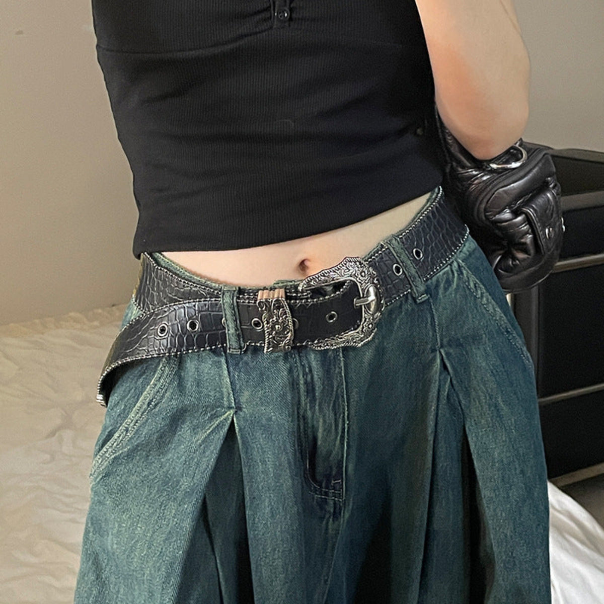 Women’s black Western-style belt with ornate silver-tone buckle styled with loose blue denim jeans