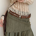 Women’s brown Western-inspired rivet belt styled with a cream blouse and olive skirt
