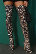 Zaria Ivory Leopard Over-the-Knee Stiletto Boots worn on a model, featuring a warm ivory and cream base with bold brown and black leopard spots, fitted thigh-high shafts, sleek pointed toes, and slender high stiletto heels for a striking statement look.